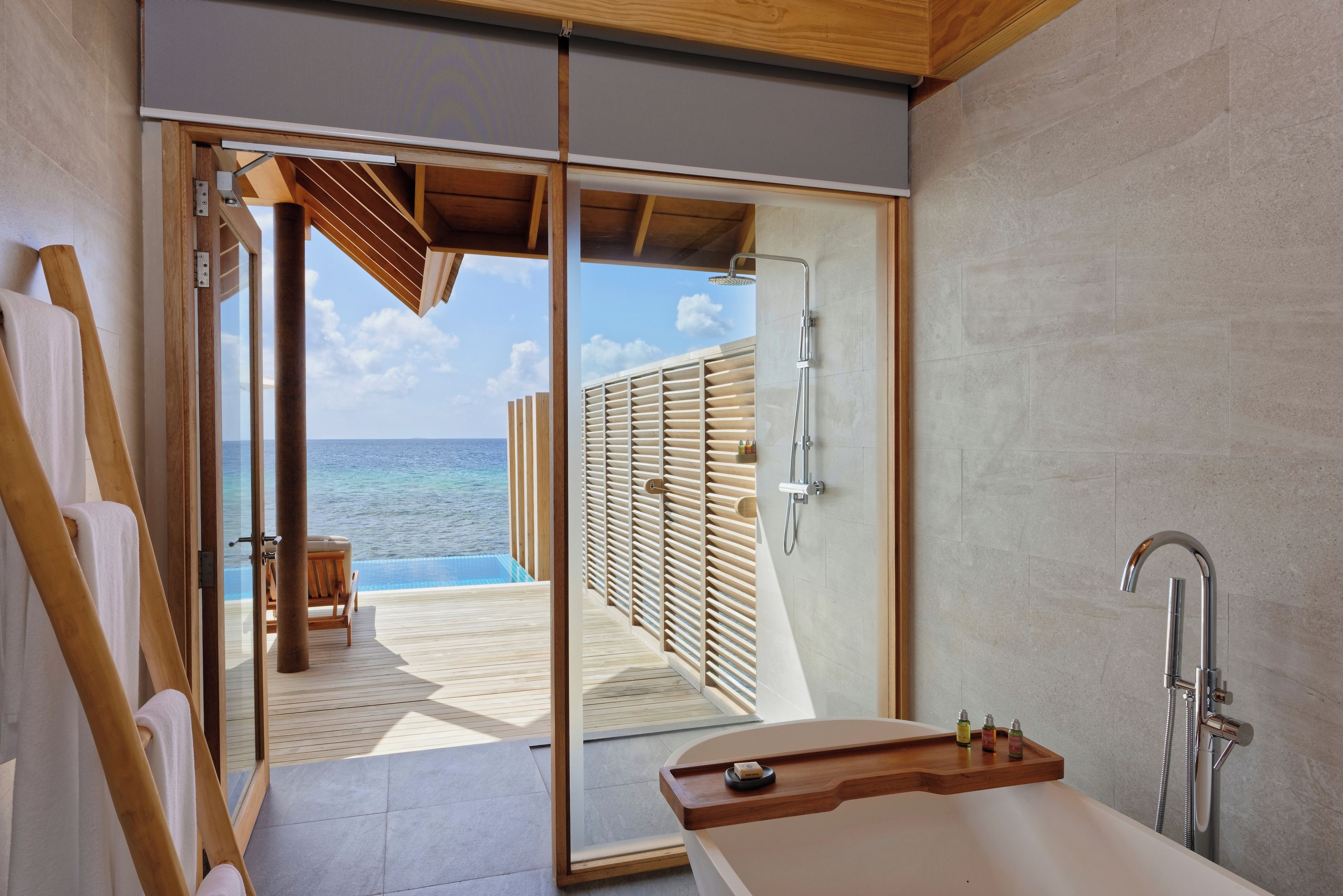 A modern bathroom with a shower, a bathtub, and a view of the ocean.