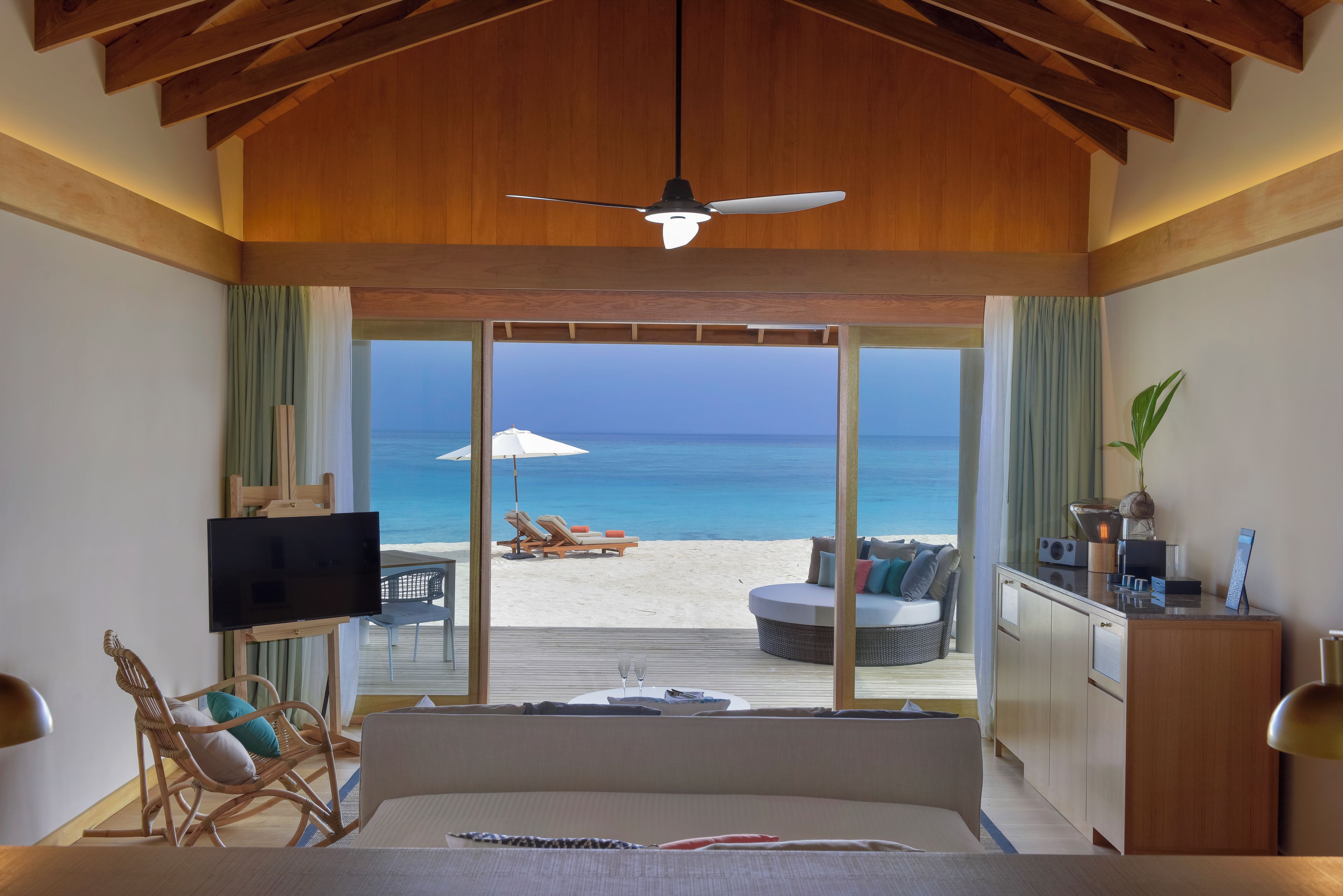 A bedroom with a large bed, a TV, and a view of the beach.