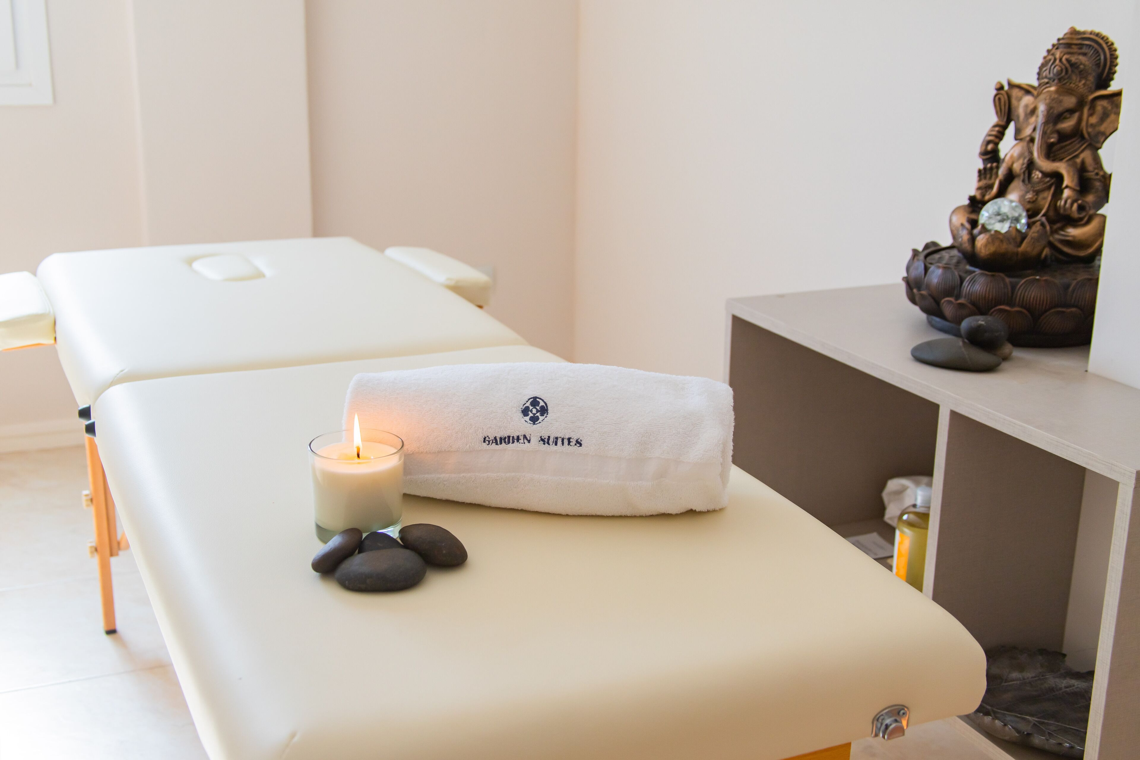 A massage table with a towel, a candle, and a statue.
