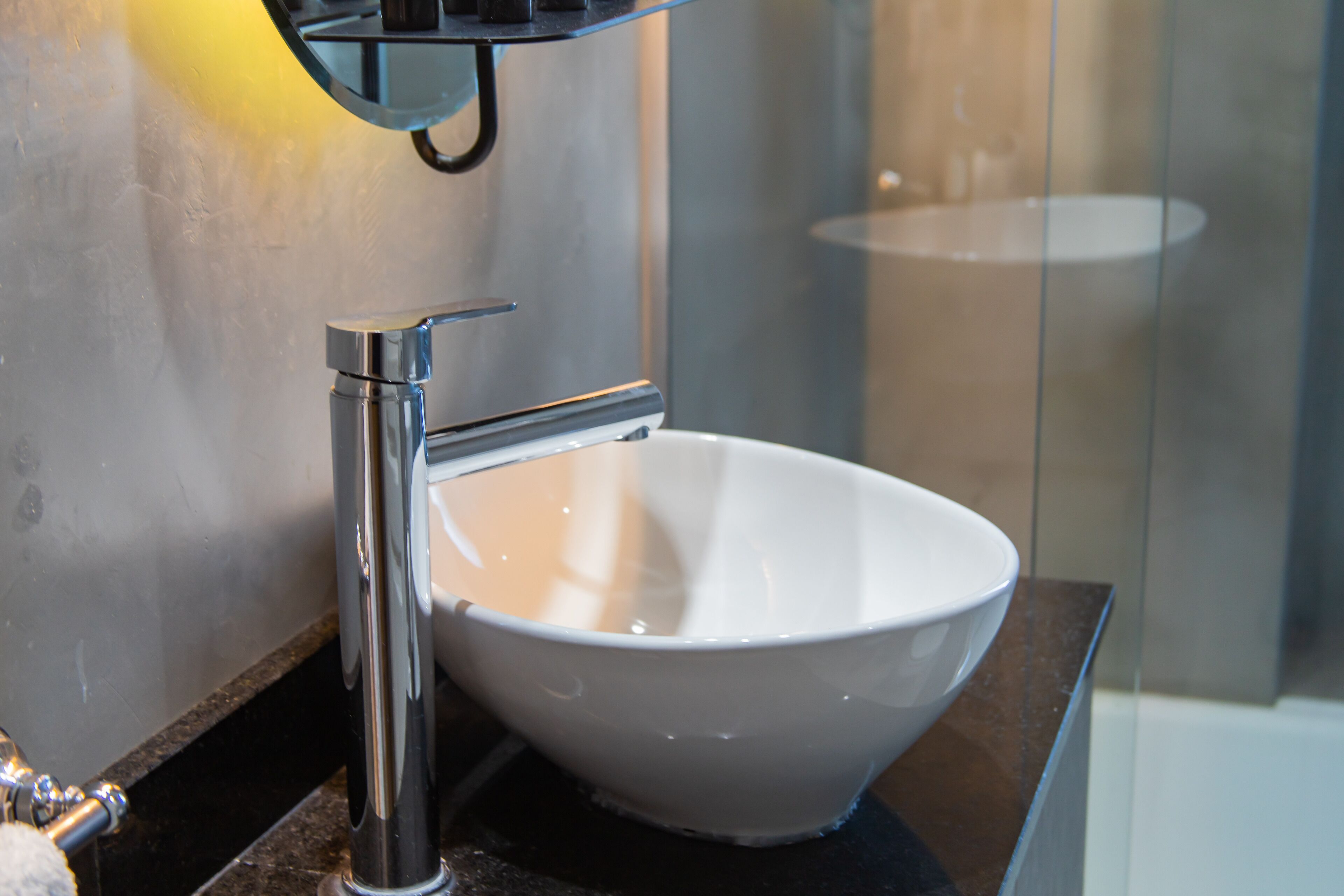 Une salle de bain moderne avec un lavabo en céramique blanche, un robinet chromé et une paroi de douche en verre.
