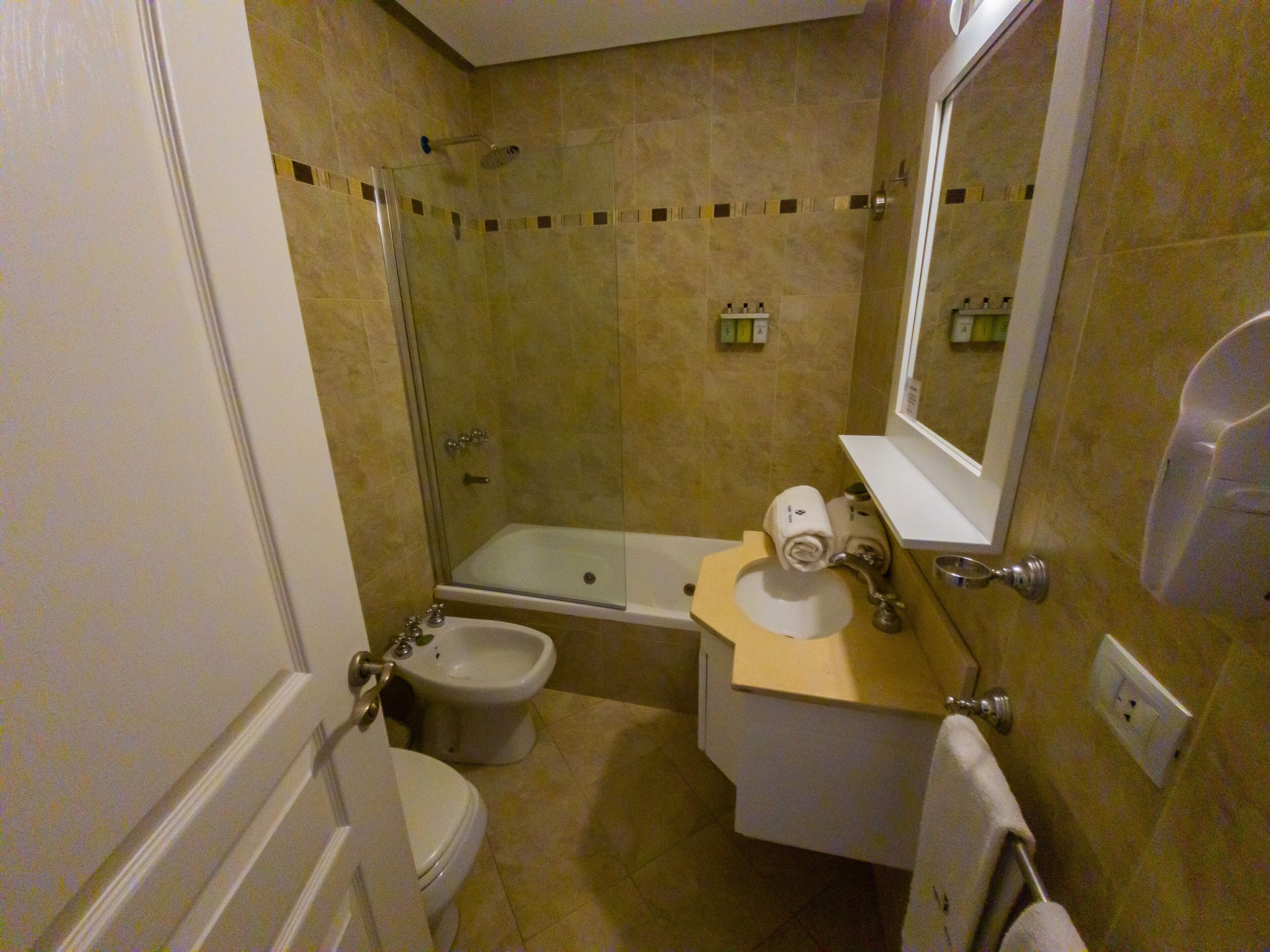 A small bathroom with a toilet, bidet, and a bathtub.