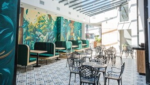 A spacious indoor area with a high ceiling, patterned floor tiles, and a variety of seating arrangements including tables and chairs. - Garden Suites Pinamar (Pinamar)