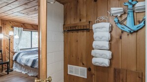 Una habitación de cabaña de madera con una cama, techo de madera y un perchero en la pared.