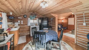 Un acogedor interior de cabaña con comedor, cocina y una pequeña sala de estar.