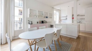 Una cucina moderna con mobili bianchi, un'isola centrale e un'area pranzo con tavolo e sedie rotonde.
