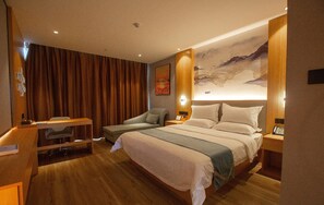 A hotel room with a large bed, a desk, a chair, and a wall with a painting. - Greentree Eastern Tongling Yian District Government Hotel (Tongling)