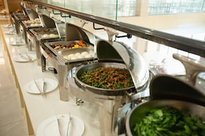 Una mesa de buffet con diversas opciones de comida, como carnes, verduras y huevos.