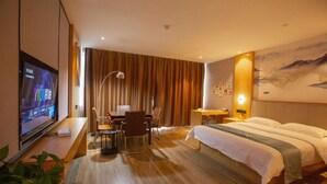 Una habitación de hotel con cama, escritorio, silla, televisor y una obra de arte en la pared.