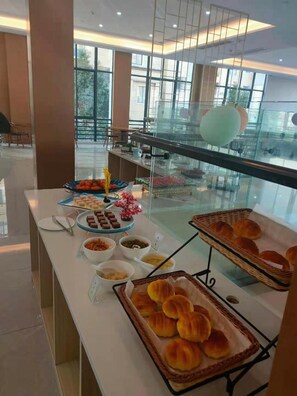 Een buffetopstelling met diverse gerechten en een glazen scheiding.