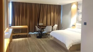 Una habitación de hotel con cama, escritorio, silla y cortinas.