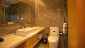 Un baño moderno con un espejo grande, un lavamanos, un inodoro y una zona de ducha.