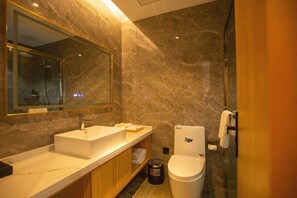 A modern bathroom with a large mirror, a sink, a toilet, and a shower area. - Greentree Eastern Tongling Yian District Government Hotel (Tongling)