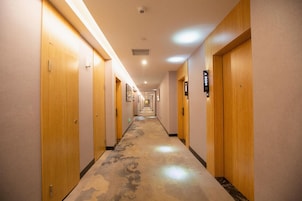 Un pasillo de hotel con puertas de madera, placas de identificación de habitaciones numeradas y piso alfombrado.