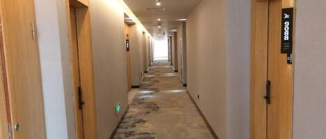 A hotel corridor with wooden doors, carpeted flooring, and a sign indicating room number 9088.