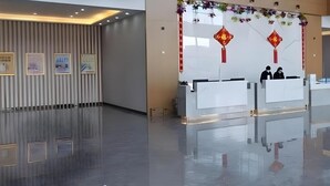 Una zona de recepción moderna con suelo pulido, obras de arte enmarcadas en la pared y un farolillo rojo decorativo.