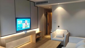 Una sala de estar moderna con una televisión de pantalla plana montada en la pared, un sofá blanco, una mesa de centro de madera y piso de madera.