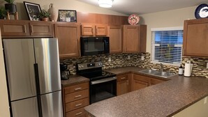 A modern kitchen with stainless steel appliances, wooden cabinets, and a granite countertop. - Bungalow w/ Heated Pool by Downtown & Beaches (Sarasota)