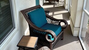 A covered porch with wicker furniture, a small table, and a door with a teal handle. - Bungalow w/ Heated Pool by Downtown & Beaches (Sarasota)