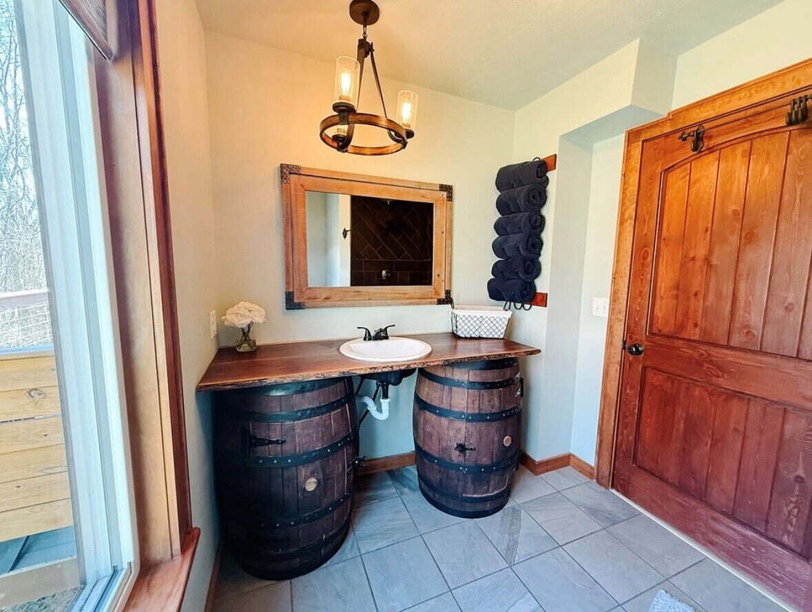 Une salle de bain avec un meuble-lavabo en bois, un miroir et une porte en bois.