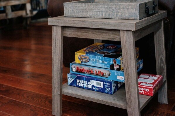 A small wooden table with three board games: 'Fool's Gold', 'Redneck Life', and 'Wheel of Fortune'.