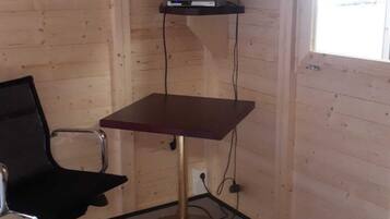 Una habitación con paredes de madera, un televisor en la pared, un escritorio con una silla y una ventana.