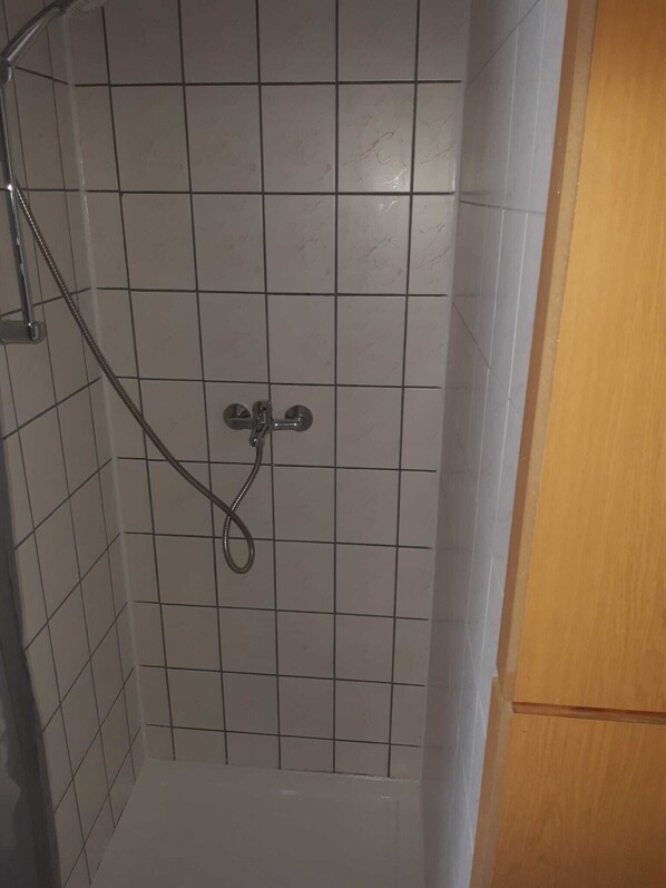 Una ducha con cabezal de ducha de mano y grifo empotrado.