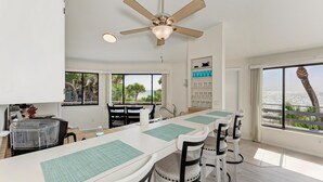 A modern kitchen with a long island, white chairs, and a ceiling fan. - The Turtle House-Miles and Miles of Private Beach-Sunset Views! (Englewood)