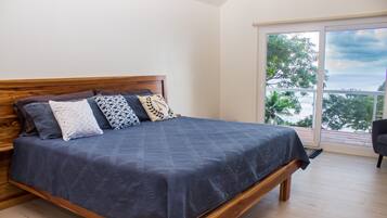 Un dormitorio con cama de madera, vista al océano y balcón.