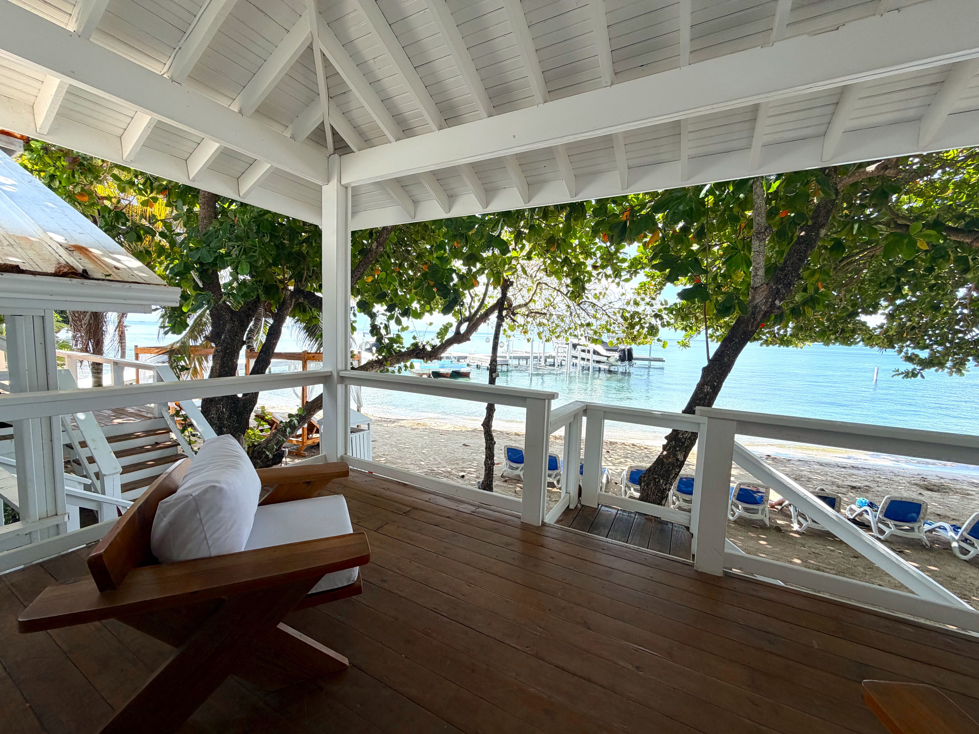 A covered outdoor seating area with wooden benches and a view of the beach and ocean.
