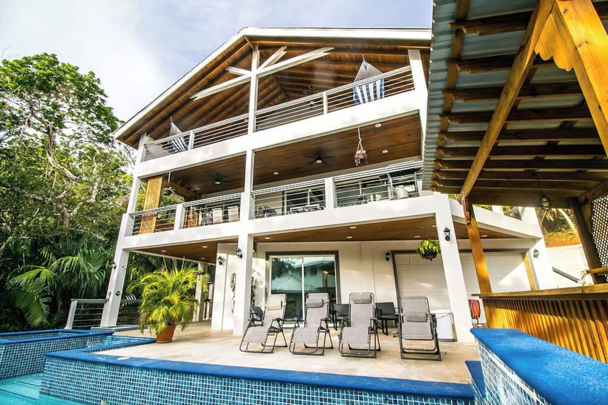 Un edificio de dos pisos con una zona de estar techada al aire libre y una piscina.