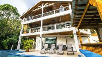 Un edificio de dos pisos con una zona de estar techada al aire libre y una piscina.