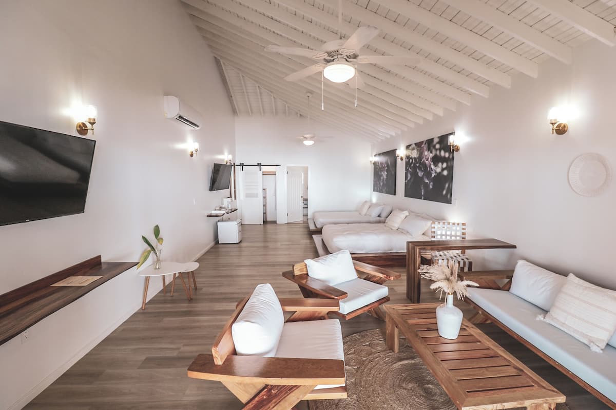Una sala moderna con ventilador de techo, televisor de pantalla plana en la pared, sofá, mesa de centro y mesa de comedor.