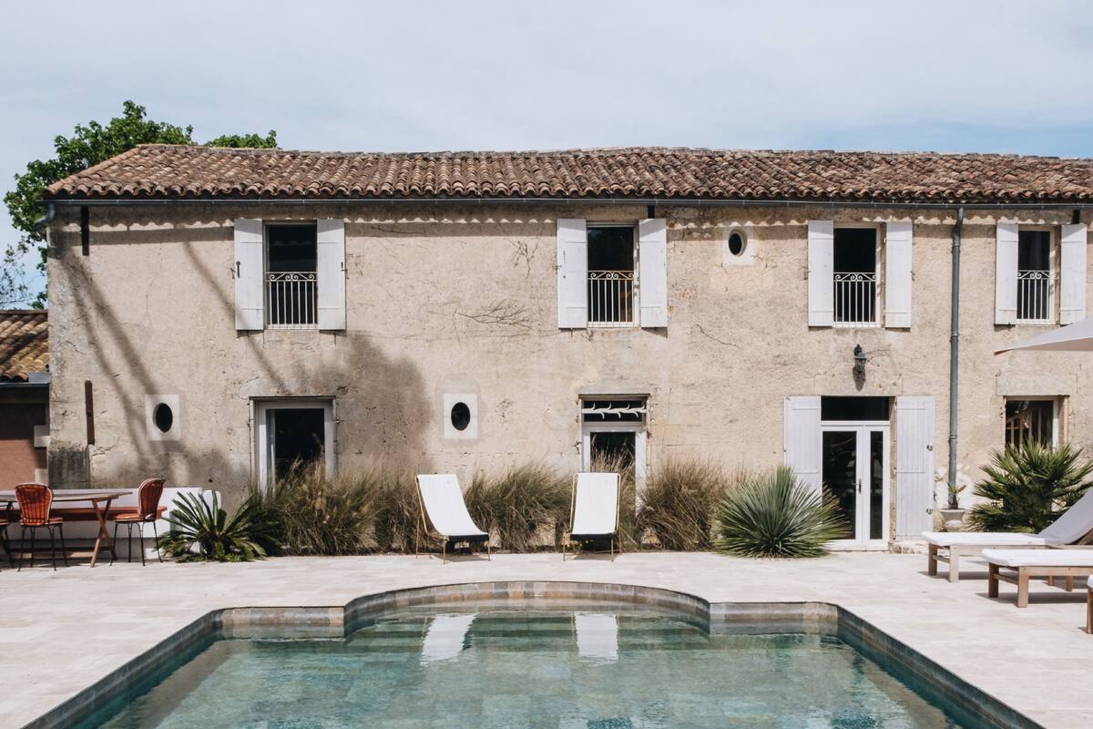 Un edificio con techo de tejas, piscina y mobiliario para exteriores.