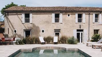 A building with a tiled roof, a swimming pool, and outdoor seating.