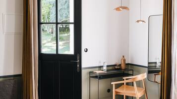 A room with a black door, a desk, a chair, a bed, and a mirror.