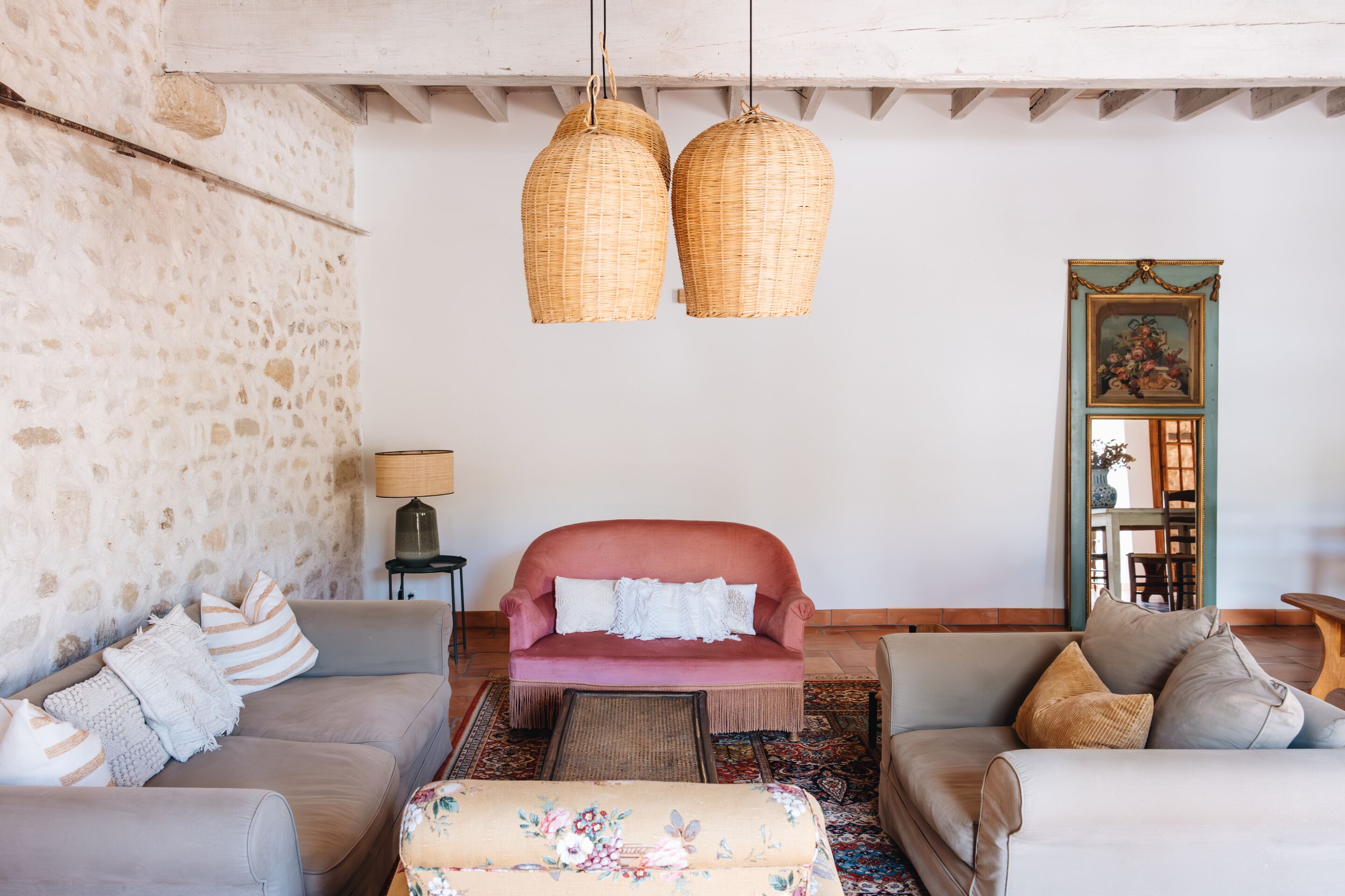 A cozy living room with a stone wall, a pink sofa, and two wicker lamps.