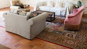 Une pièce rustique avec des murs en pierre, un plafond en bois, un tapis à motifs et un canapé.