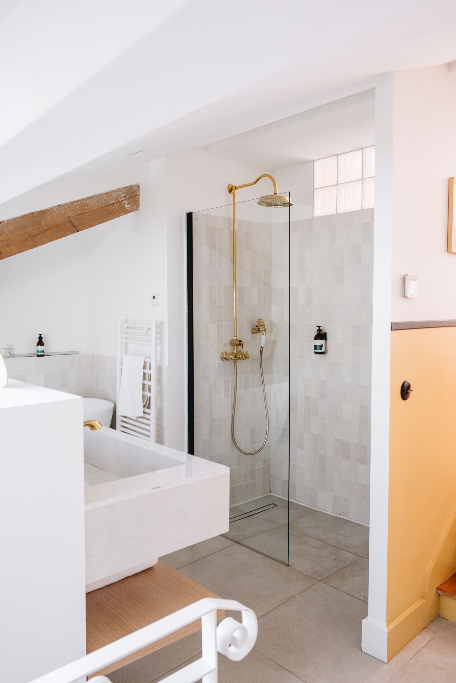 Ein modernes Badezimmer mit einer gläsernen Duschkabine, einem weißen Waschtisch und einer Holzbalkendecke.