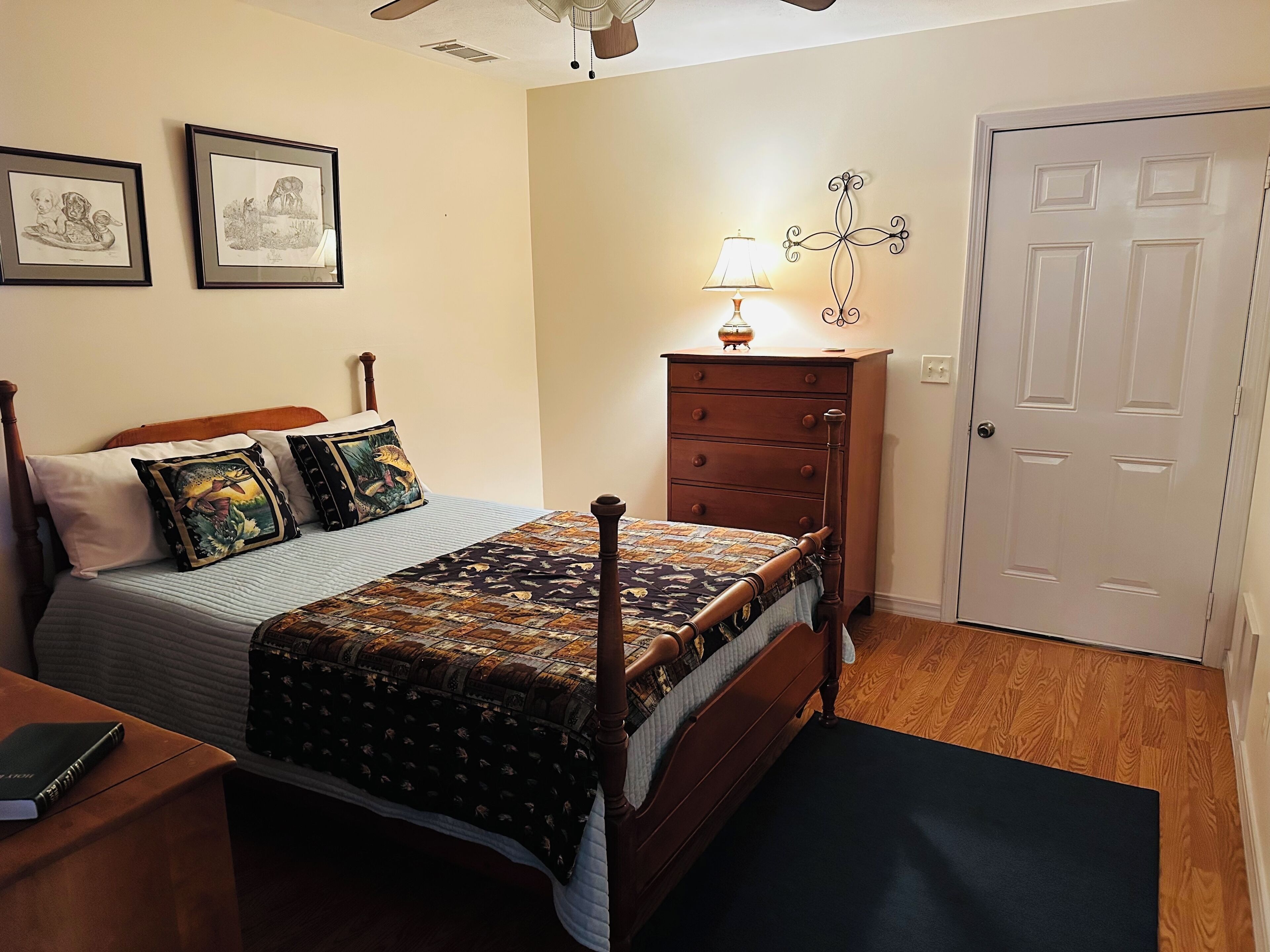 Un dormitorio con una cama de madera, una mesita de noche, un aparador, una lámpara y una puerta.