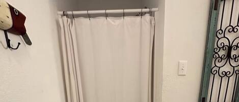 A bathroom with a shower curtain, a towel rack, a hand dryer, and a mat with "Happy Jack's" written on it.