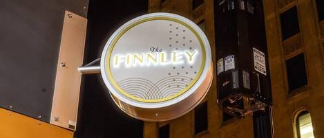 A neon sign for "The Finnley" against a historic building facade at night.