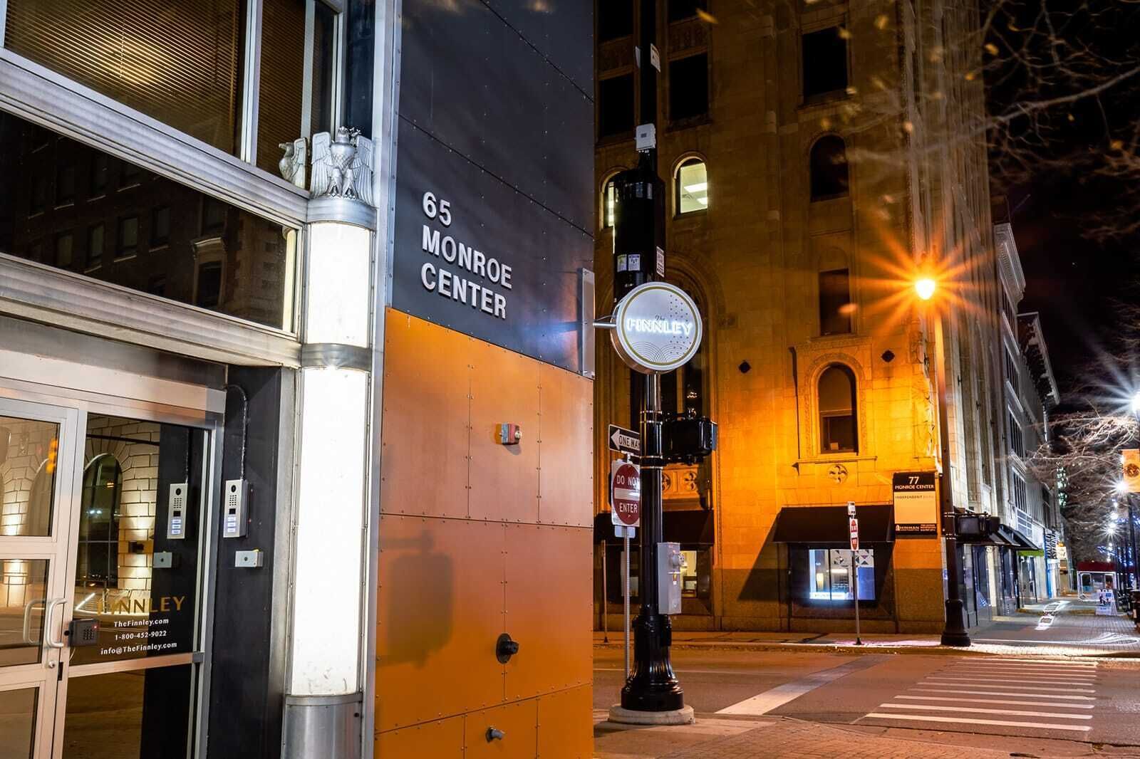 A building facade with a sign for '65 MONROE CENTER' and a 'ONE WAY' street sign.