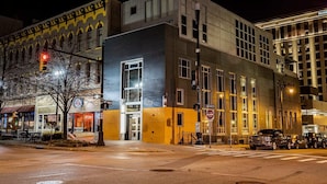 A modern building with a large entrance, a visible sign for '65 Monroe Center', and a 'Do Not Enter' sign on the street. - The Finnley (Grand Rapids)