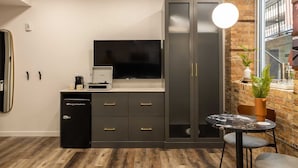A modern room with a large flat-screen TV, a built-in sound system, a compact kitchen area, and a small dining table with two chairs. - The Finnley (Grand Rapids)