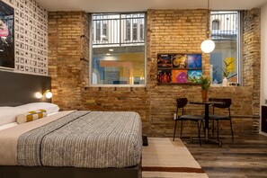 Une chambre avec un mur en briques, un lit, un bureau et une chaise.