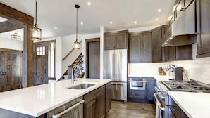A modern kitchen with a large island, stainless steel appliances, and wooden cabinetry.