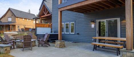 A building with a covered patio area featuring outdoor seating and a barbecue grill.