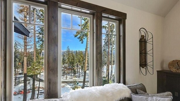 A cozy room with a large window offering a view of a snowy forest.