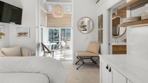 Une chambre moderne comprenant un lit, un coin salon avec des fauteuils, une table à manger et un coin cuisine avec des placards et un évier.