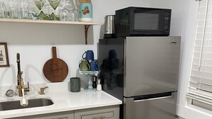 Une cuisine équipée d’un réfrigérateur en acier inoxydable, d’un four à micro-ondes, d’un évier et d’une planche à découper en bois.